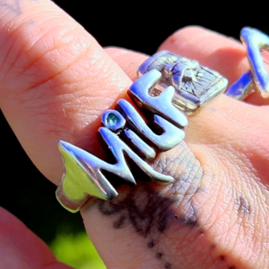 Chunky sterling silver MILF ring with gothic arrow details and a blue gemstone accent. Fierce handmade jewellery with feral energy.
